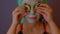 Woman with mask on face holds cucumber slices on eyes. Relaxed lady caring of her face with cosmetic mask and fresh