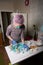 A woman in a mask, hat and rubber gloves makes marshmallows. Nearby is a zephyr in a waffle cone. Everything is laid out on the