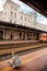 Woman in a mask on the platform near the train. The girl is sitting at the train station near the train. Travel by rail. View of a