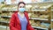 Woman in mask standing in bakery against shelves with bread