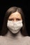 A woman in a mask , a tense, restless look at the camera. concern about a coronavirus infection , an attempt at