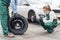 Woman mechanic checking spare wheel near car