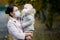 Woman in a medical face mask holds a crying baby girl in her arms