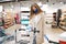 Woman with medical face mask wipes the shopping cart handle with a disinfecting cloth in supermarket