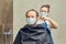 A woman in medical mask cuts a man hair with scissors in the bathroom close up. The concept of closed salons and barbershop during