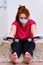 A woman in a medical mask with dumbbells does sports in the home kitchen. Independent fitness training in isolation due to the