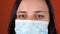 Woman with medical mask on her face. Close-up of woman`s crying eye. Concept of coronavirus epidemic or diseases.