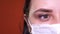 Woman with medical mask on her face. Close-up of woman`s crying eye. Concept of coronavirus epidemic or diseases.