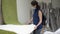 A woman with a medical mask on her face examines and evaluates before buying a white carpet in an empty shopping hall of