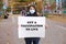 A woman in a medical mask holds a poster that says Get a vaccination to live