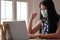 Woman in medical mask raising her fist with laptop on desk while working from home, Work from home