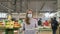 Woman in a medical mask and rubber gloves stands with a grocery cart in a supermarket against the background of shelves