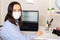 Woman in medical mask wrote word covid-19 on monitor screen, remote work at home, coronavirus, pandemic