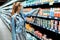 Woman in a medical protective mask on her face buys food at a supermarket. a young lady buys dairy products at a grocery store.