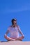 Woman meditate sits sandy beach on blue sky background yoga practice pose.