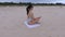 Woman meditates on beach near sea