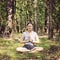 woman meditating alone and silent in summer forest