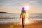 Woman is meditating with glowing seven chakras on the beach. Silhouette of woman is practicing yoga at sunset