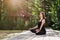 Woman meditating in lotus position on wooden walkway outdoors