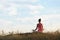 Woman meditating in meadow, back view