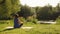 Woman meditating in park at sunrise. Female sitting in lotus position on fitness mat and practicing yoga. Lady doing yoga outdoors