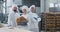 Woman and men bakers in a big bakery industry smiling large to the camera while holding a basket of organic bread