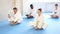 Woman and men in kimonos doing stretching butterfly before karate ore judo training