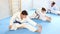 Woman and men in kimonos doing stretching before karate ore judo training