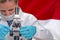 Woman with a microscope against Indonesia flag background. Medical technology and pharmaceutical research in Indonesia