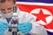 Woman with a microscope against North Korea flag background. Medical technology and pharmaceutical research in North Korea