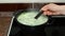 Woman mixes cheese soup in a saucepan on stove