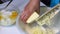 A woman mixes the ingredients to make a marble cake. Grinds butter on a grater into a dough. Next to the table are other ingredien