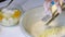 A woman mixes the ingredients to make a marble cake. Grinds butter on a grater into a dough. Next to the table are other ingredien