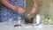 A woman mixes nut butter in a blender bowl. Walnut urbech. The ingredients are on the table side by side