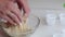 A woman mixes peanut butter, chocolate and coconut flour to make candy. Nearby on the table are paper candy tartlets. Close-up