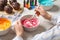 Woman mixing cream with pink food coloring at white wooden table, closeup. Decorate cupcakes