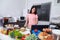 Woman mixing salad while cooking with laptop in kitchen