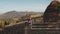 Woman with mobile at mountain aerial. Autumn nature landscape. Girl tourist on wood fence. Haystack