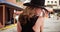 Woman modeling black hat in shopping district downtown, back to camera