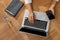 Woman with modern smartphone and laptop at wooden table, top view. Searching information