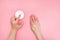 Woman moisturizing her hand with cosmetic cream with copy space on pink background in minimalism style.