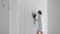A woman in a moisturizing mask on her face carries a vase of white chrysanthemums to the bathroom in the morning