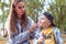 Woman mom wipes child cheeks and lips with ice-cream from ice cream, in summer in park, little boy eats ice cream