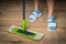 Woman with mop mopping wooden laminate floor