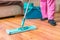 Woman is mopping wooden floor with mop