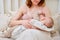 Woman mother breastfeeds infant baby boy sitting on home bed. Mom feeds milk toddler child in the bedroom