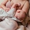 Woman mother breastfeeds an infant baby sitting on a home sofa. Mom feeds milk toddler baby in living room