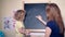 Woman mother and girl daughter writing word mother with chalk on black board