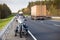 Woman on a motorcycle stands on the roadside of a country highway near passing freight truck