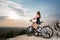 Woman with the mountain bike under a sky at sunset